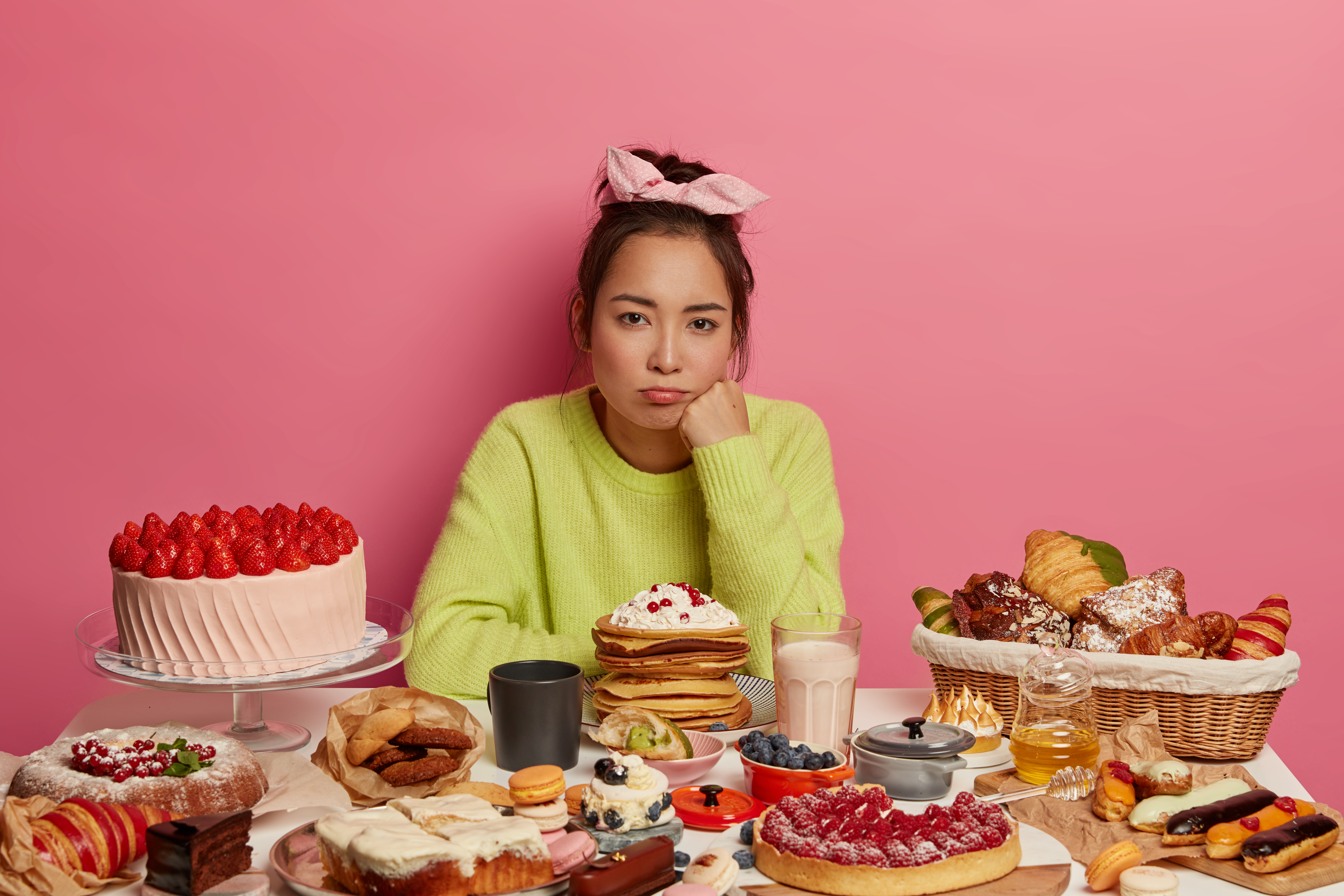 üzgün kadın şekerli yiyeceklerle dolu masanın önünde