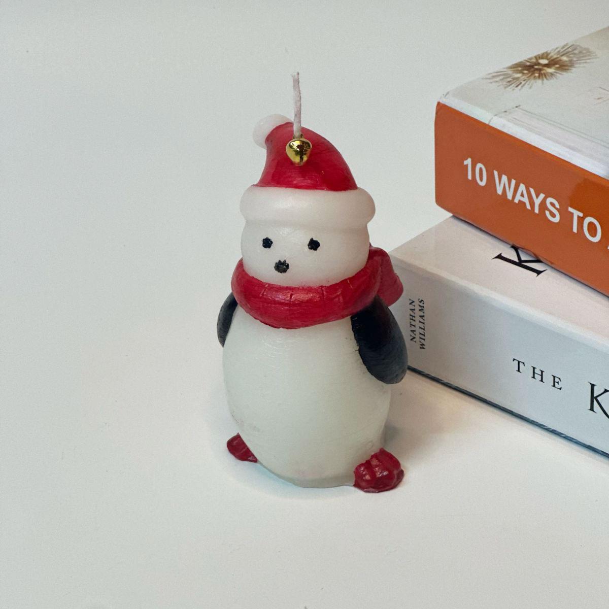 11 cm yüksekliğinde kokulu penguen figürlü mum. Kırmızı şapka ve atkısı olan, dekoratif yılbaşı mumu.