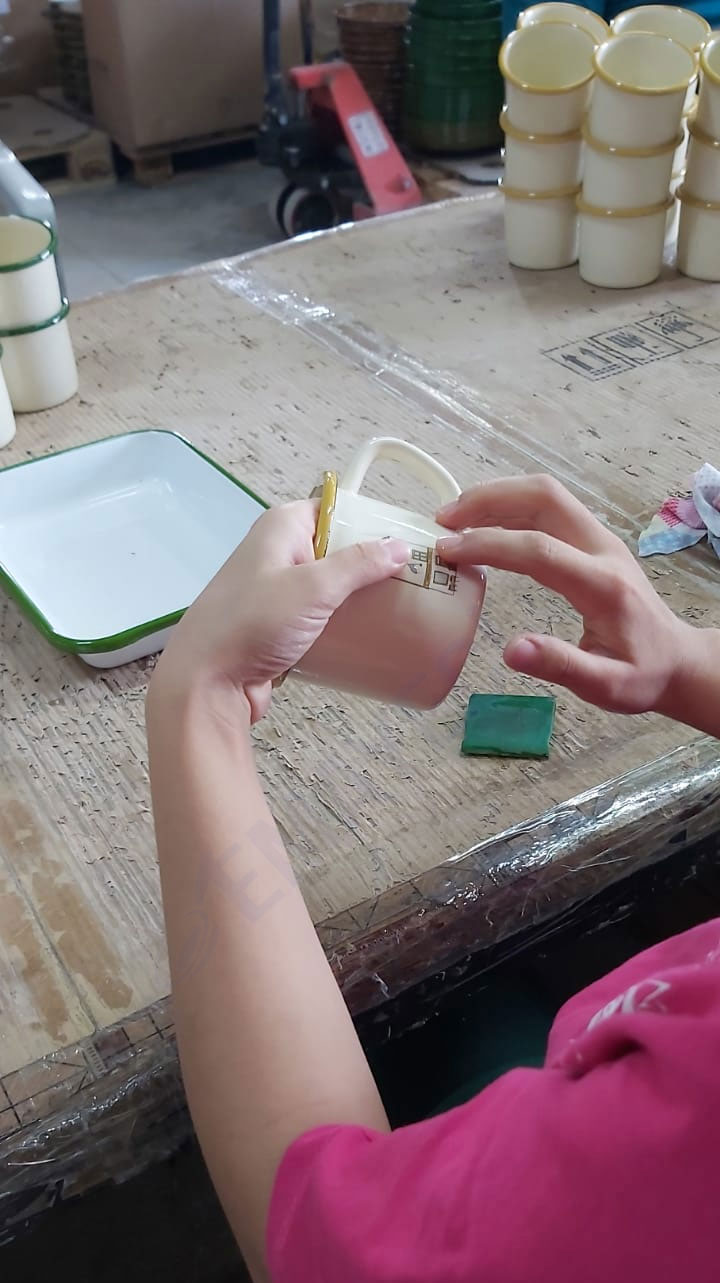 Emaye kupa üzerine el işçiliği ile uygulanan dekal baskı ve desen transferi aşaması.