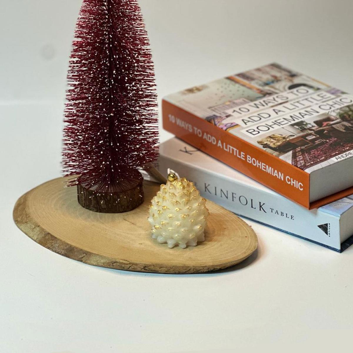 7 cm yüksekliğinde, beyaz renkli, altın yaldız detaylı kokulu kozalak figürlü mum. Dekoratif kış, yılbaşı ve doğa konsepti mumu.