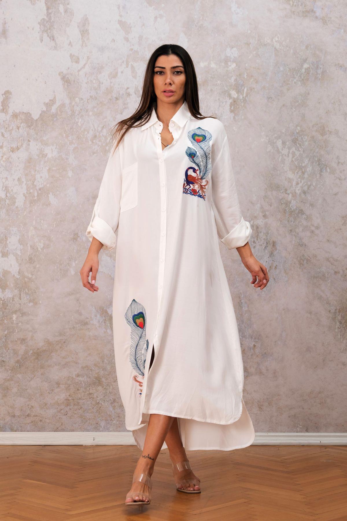 فستان أبيض بقميص طويل مزين بتطريز طاووس على الصدر والتنورة وأكمام بأكمام وجيوب مزينة بجيوب