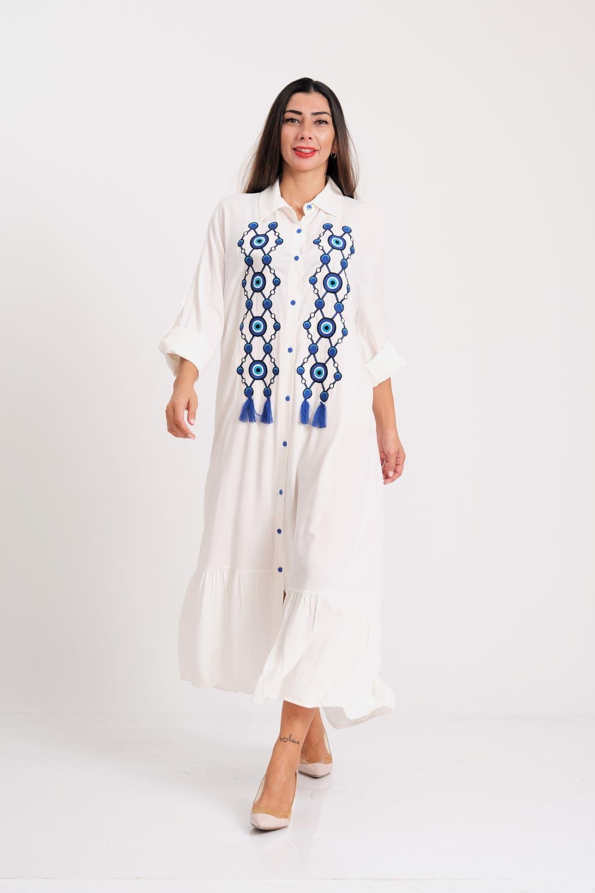 فستان أبيض طويل بقميص طويل مع شرابات مطرزة بالخرز على شكل عين الشر من الأمام وحافة مكشكشة مع كتاف على الأكمام