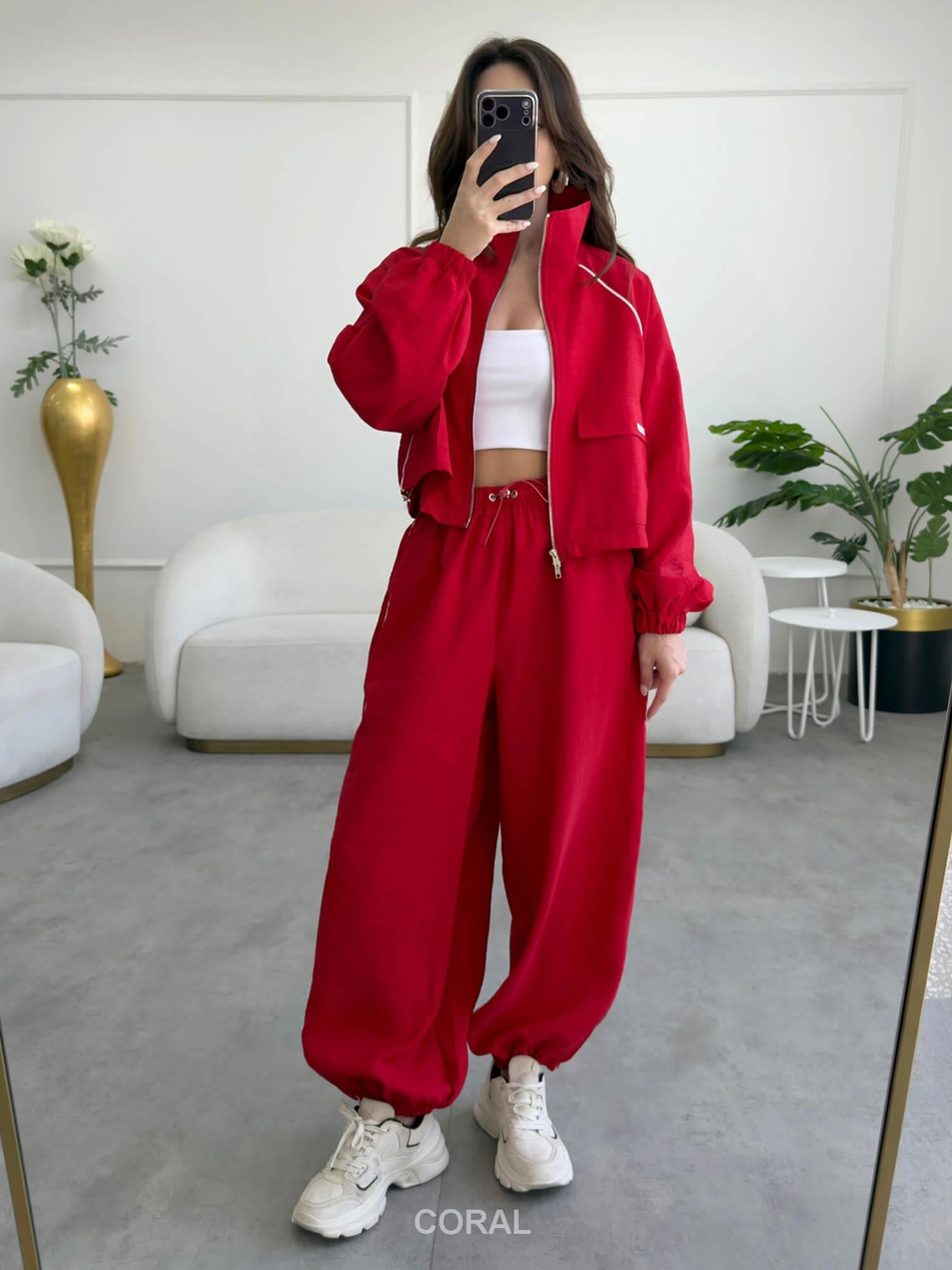 Coral Shop kırmızı biyeli paçası lastikli paraşüt pantolonun beyaz üst ve kırmızı ceketle sportif kombini