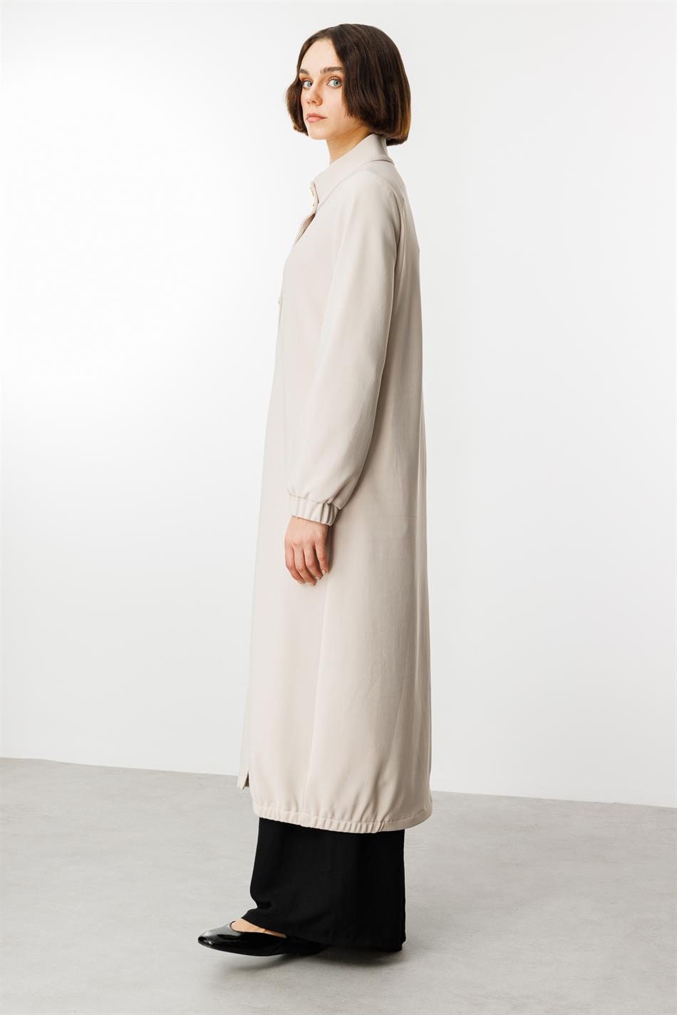 Tijdloze sportieve trenchcoat met gouden details en gedrapeerde stof.