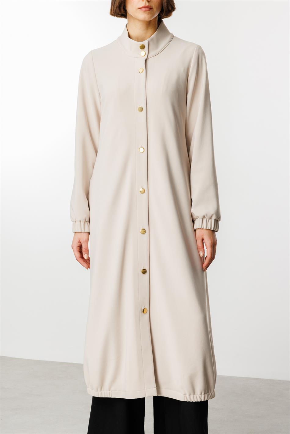 Tijdloze sportieve trenchcoat met gouden details en gedrapeerde stof.