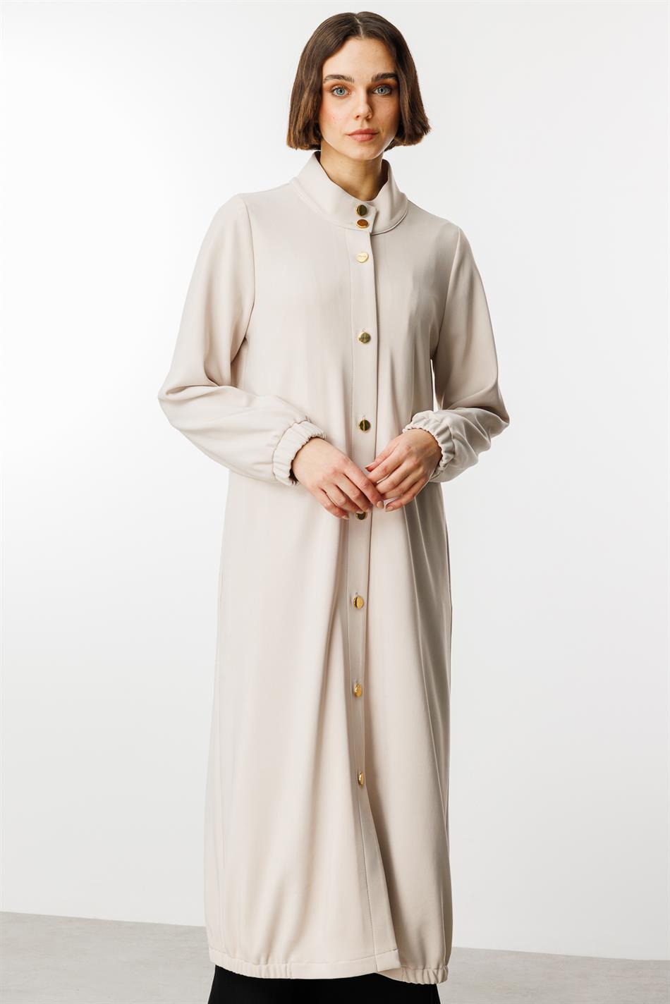 Tijdloze sportieve trenchcoat met gouden details en gedrapeerde stof.
