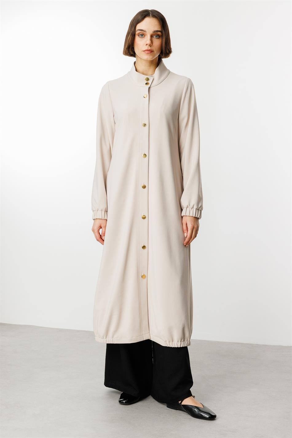 Tijdloze sportieve trenchcoat met gouden details en gedrapeerde stof.