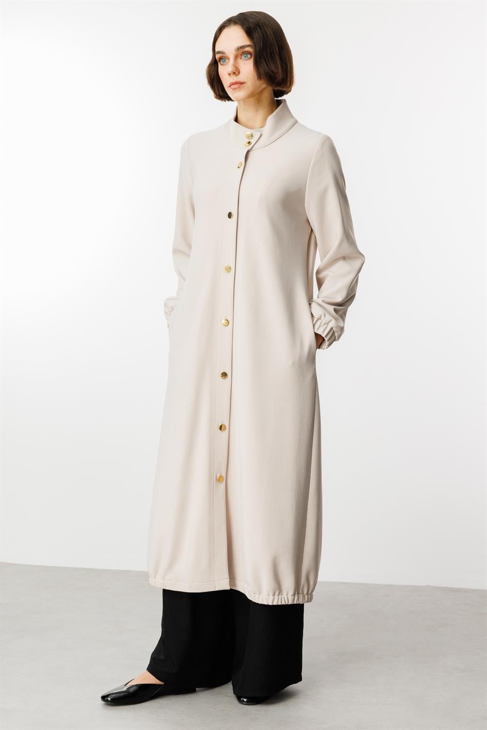 Tijdloze sportieve trenchcoat met gouden details en gedrapeerde stof.