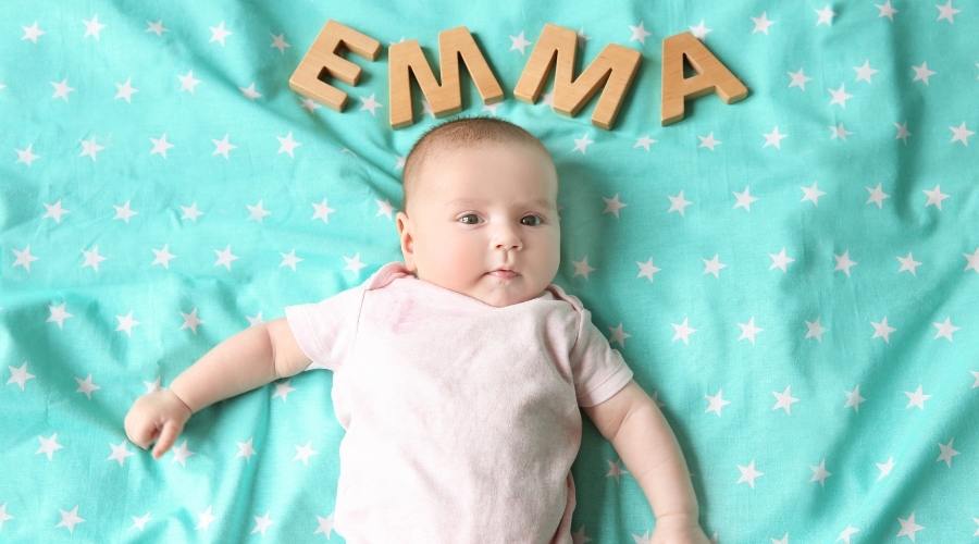 Yabancı kız isimleri arasında yer alan emma ismini harflerle yatakta bebeğinin yanına yazan ve bebeğine emma ismini koyduğunu gösteren ebeveyn