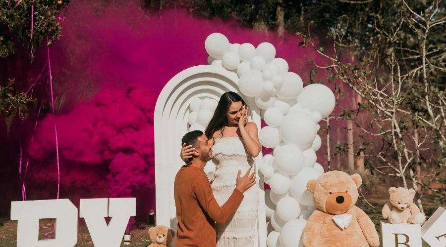 Cinsiyet partisi fikirleri arasından balon patlatma ile pembe tozları gören ve kız bebekleri olacağını öğrenen anne baba adayı.