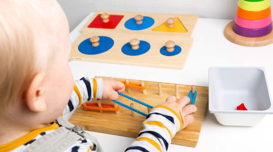 Sarışın bebek ince motor becerileri ve duyusal oyunlar için Montessori materyalleriyle çalışıyor.