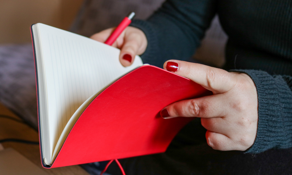 evde nişan hazırlıkları listesi için kırmızı defter ve kalem görseli
