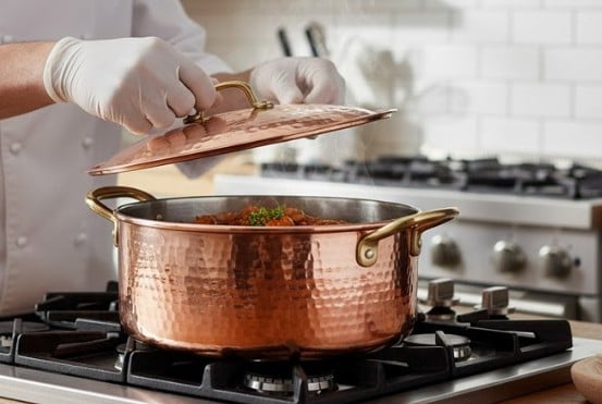 Bakır tencerelerede yemek bişiren Aşçı