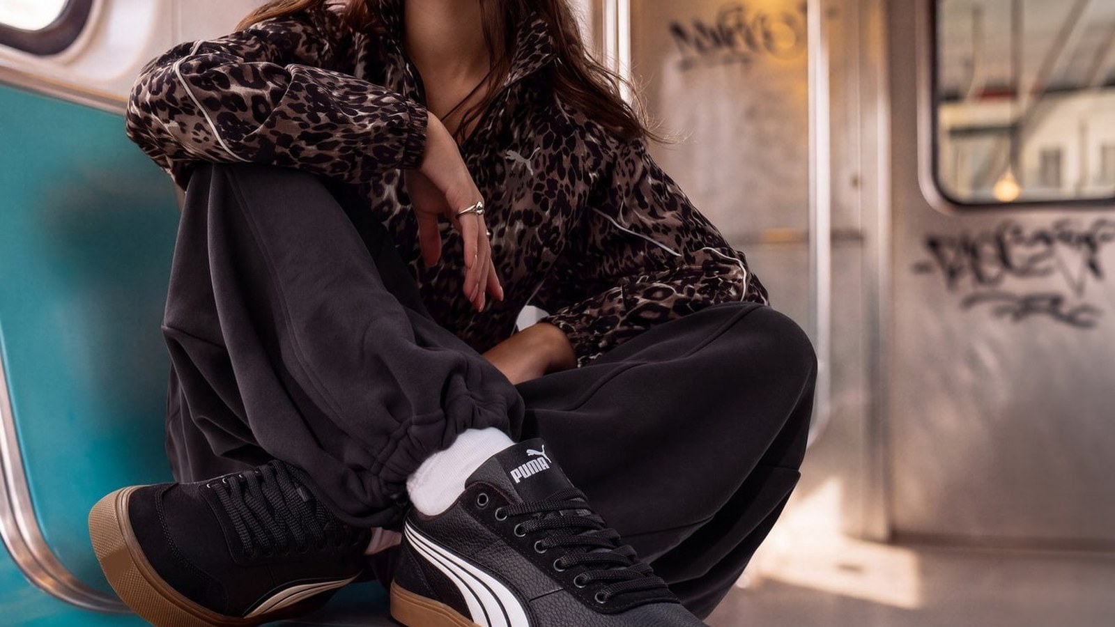Metroda oturan genç kadının ayağında siyah Puma sneaker, Kasım indirimleri yazısı kapağı