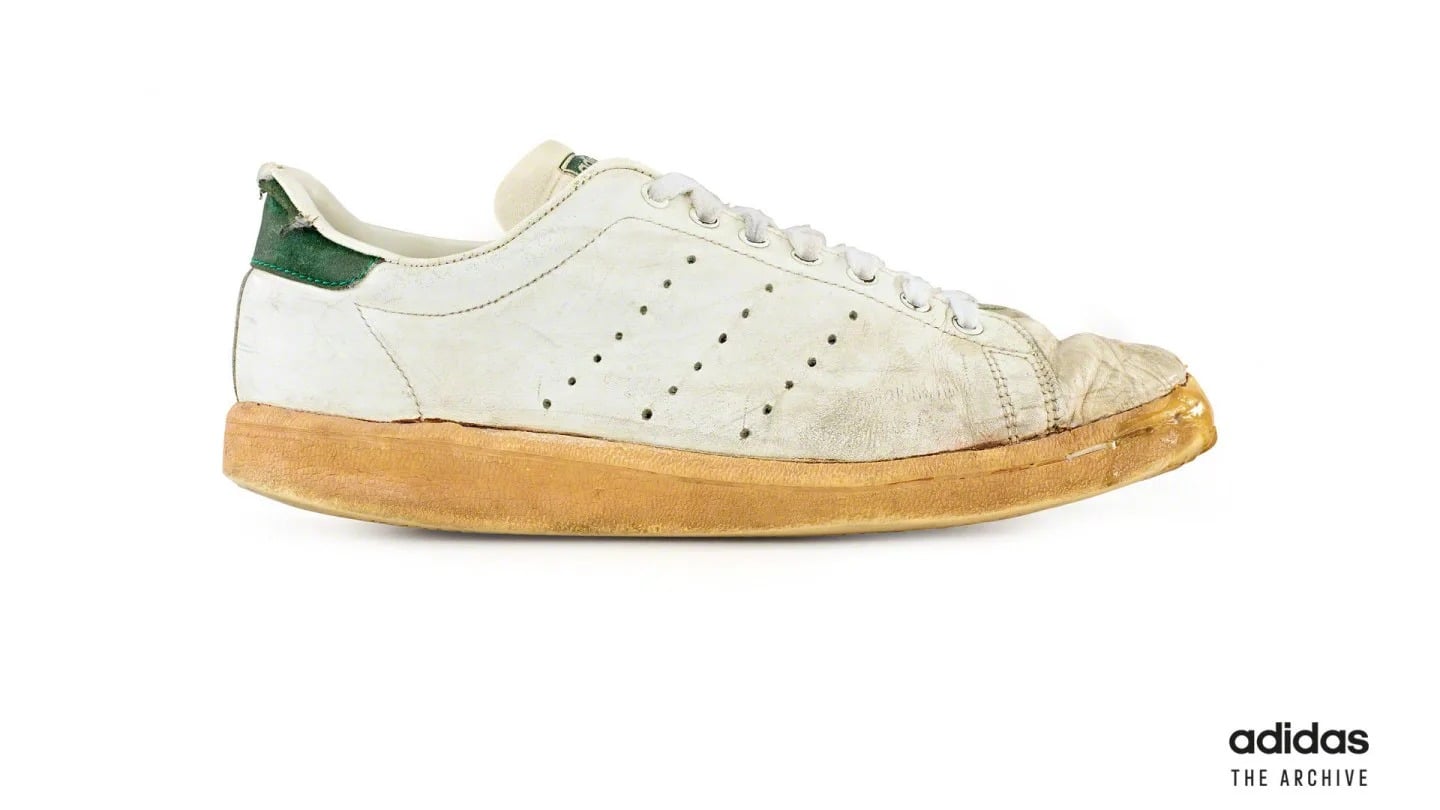 adidas arşivinden Stan Smith'in erken bir sürümü: beyaz deri üst yüzey, yanda delikli üç şerit, yeşil topuk parçası, yıllanmış krem rengi taban