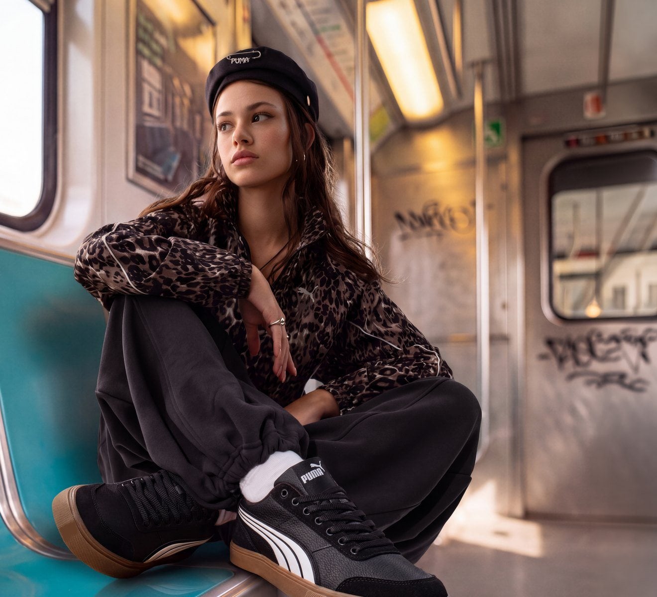 Metroda oturan genç kadın, ayağında siyah Puma sneaker