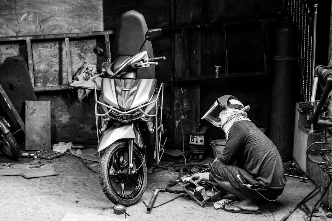 motosiklet tamirhane, yedek parça düzeni, motosiklet bakım ekipmanları, modern tamir atölyesi, motosiklet lift üzerinde, motor parçaları rafları, temiz ve düzenli tamirhane, teknik motosiklet ekipmanları, profesyonel motosiklet servisi, yedek parça blog görseli