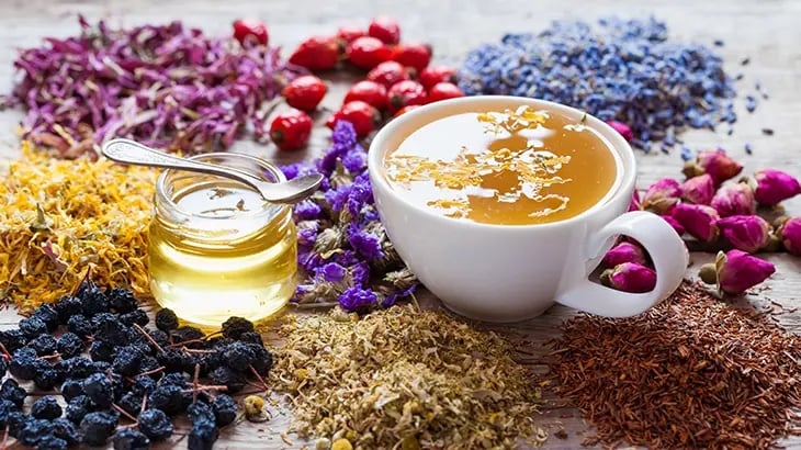 Çay demleme püf noktalarını anlatan kuru çiçekler ve fincanda bitki çayı