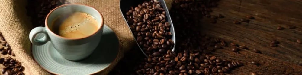 Dünya Kahve Günü için çuvaldan dökülen çekirdekler ve fincanda kahve