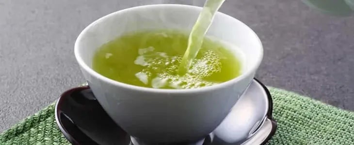Yeşil çayın beyaz kâseye dökülerek servis edilmesi