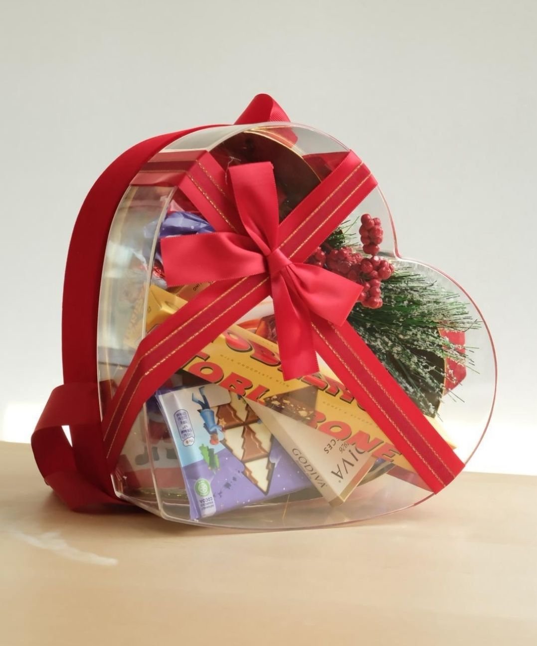 Sevgililer günü için kırmızı kurdeleli şeffaf kalp hediye kutusu ve premium çikolatalar