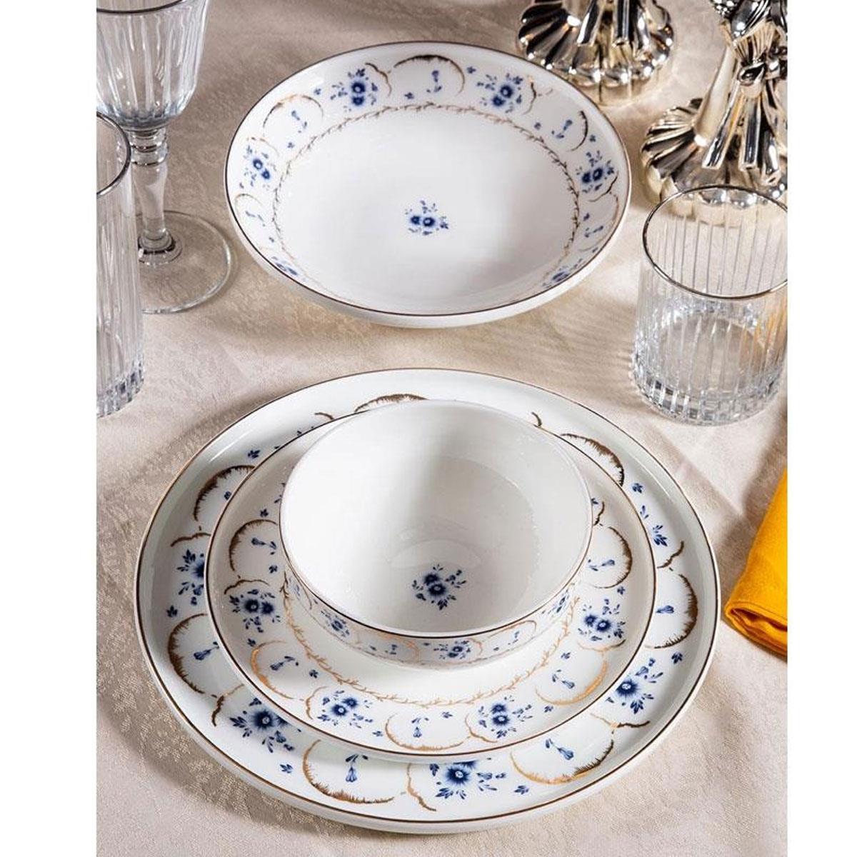 Massimo Bluegarden Gold yemek takımı, servis tabağı, kase ve çorba tabağı ile kurulmuş lüks bir sofra görünümü. Mavi çiçek desenleri ve gold detaylar, kristal bardaklarla kombinlenmiş.