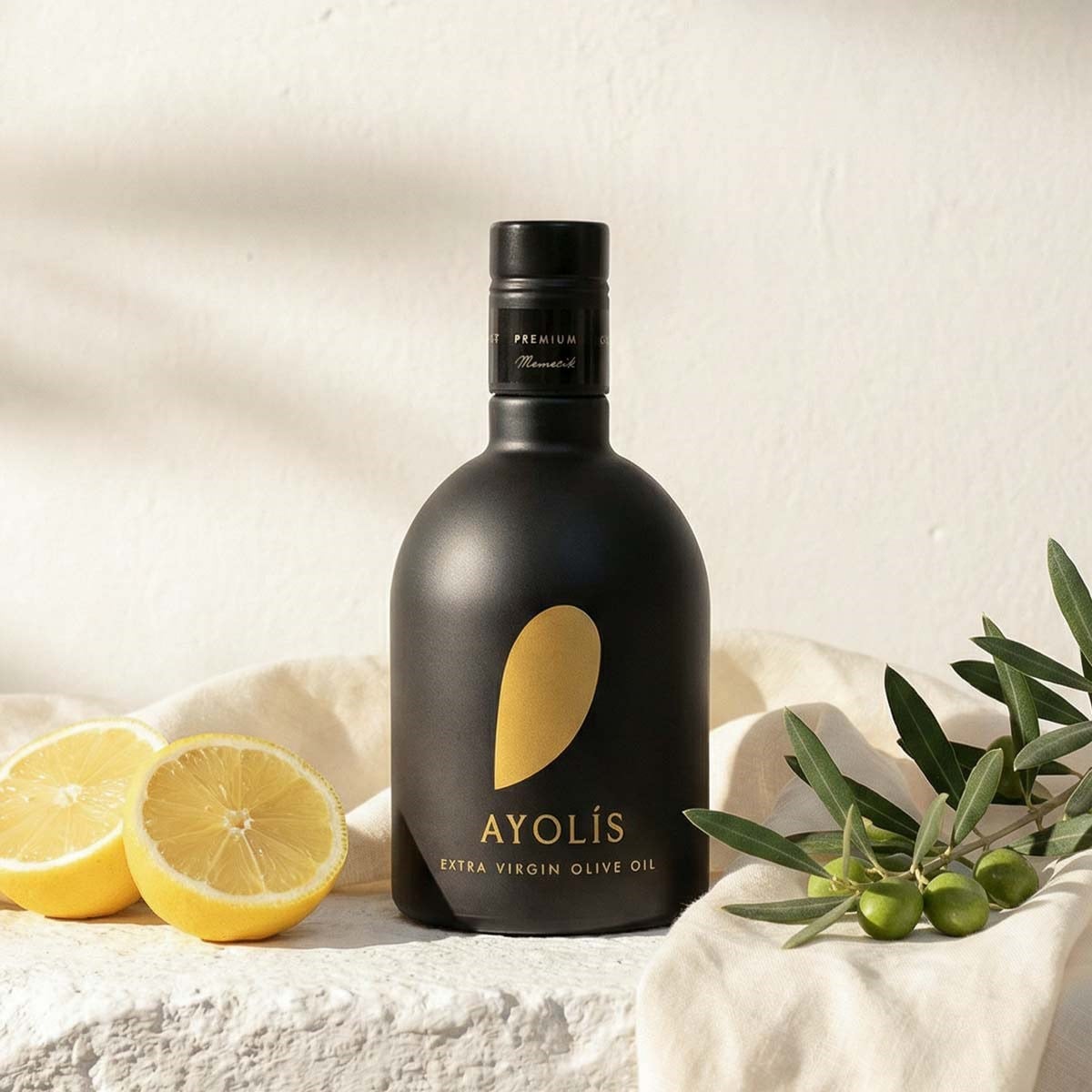 Ayolis Premium Gurme Memecik 500 ml zeytinyağı şişesi, limon ve zeytin dalı ile sunum