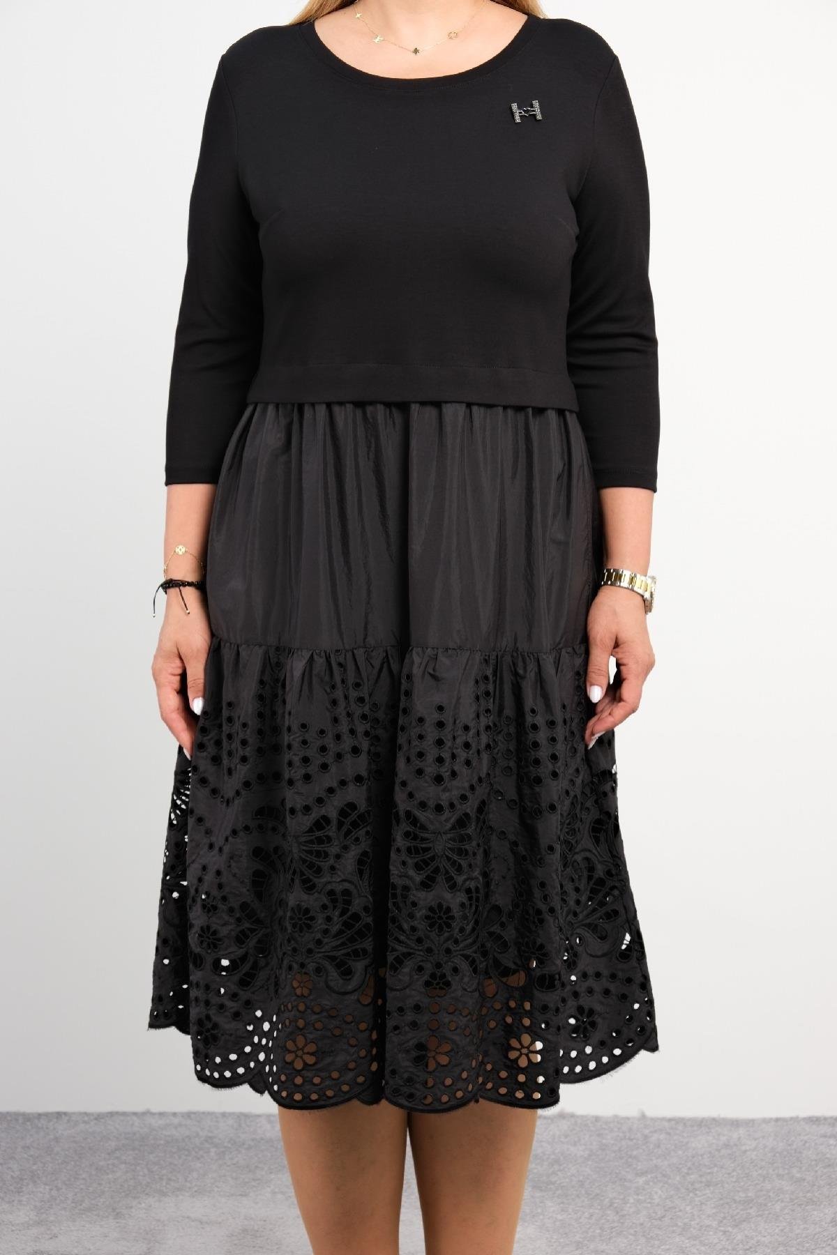  Bu elbise, diz altı uzunluğunda ve siyah renktedir. Üst kısmı sade ve uzun kollu, alt kısmı ise incelikli dantel işlemeleriyle süslenmiş, katmanlı bir tasarıma sahiptir. Ürün rahat bir kesime sahip olup, günlük kullanım için idealdir. Üst kısmı düz 