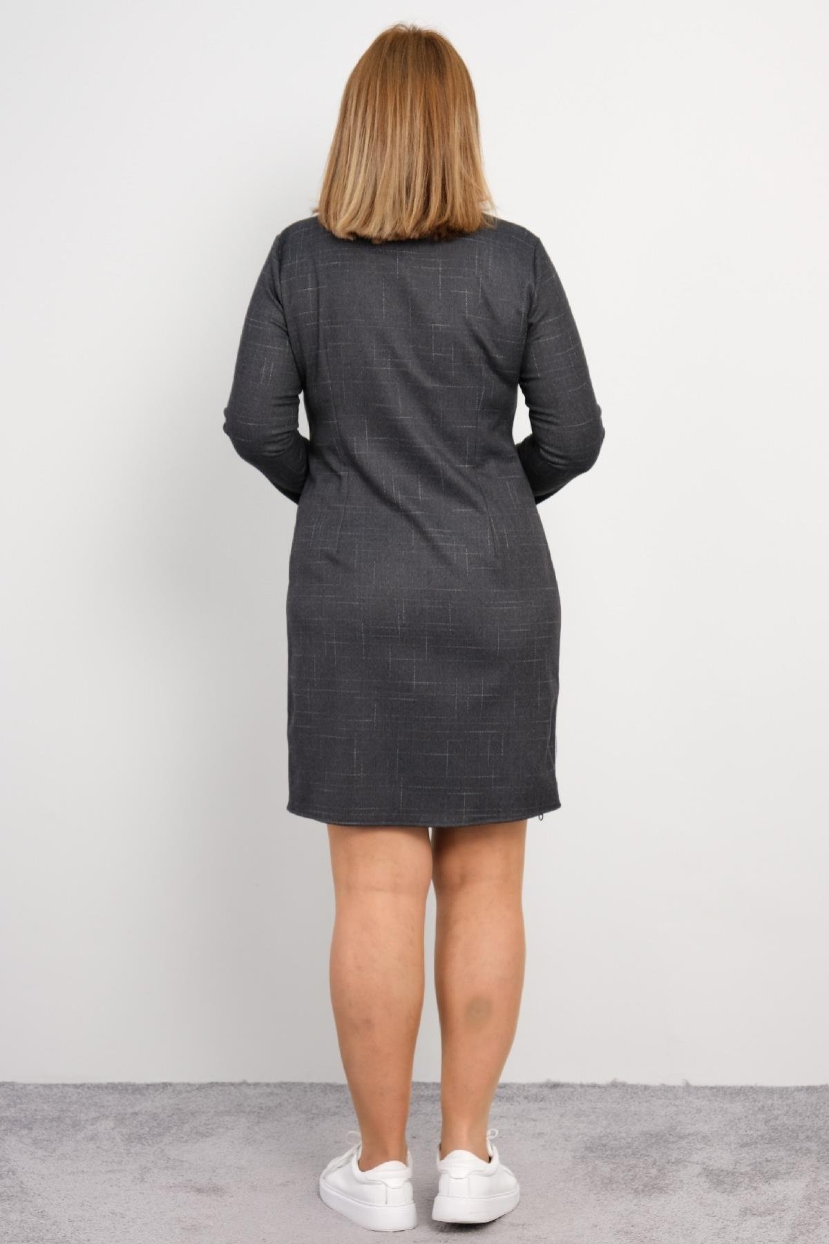  Bu elbise, koyu gri renkte, uzun kollu ve diz üstü uzunluğundadır. Ürünün ön kısmında bir fermuar detayı bulunur ve yanlarda beyaz şerit detayı vardır. Elbisenin bel hizasında iki adet cep bulunmaktadır. Arka kısmı düz ve sade bir tasarıma sahiptir.