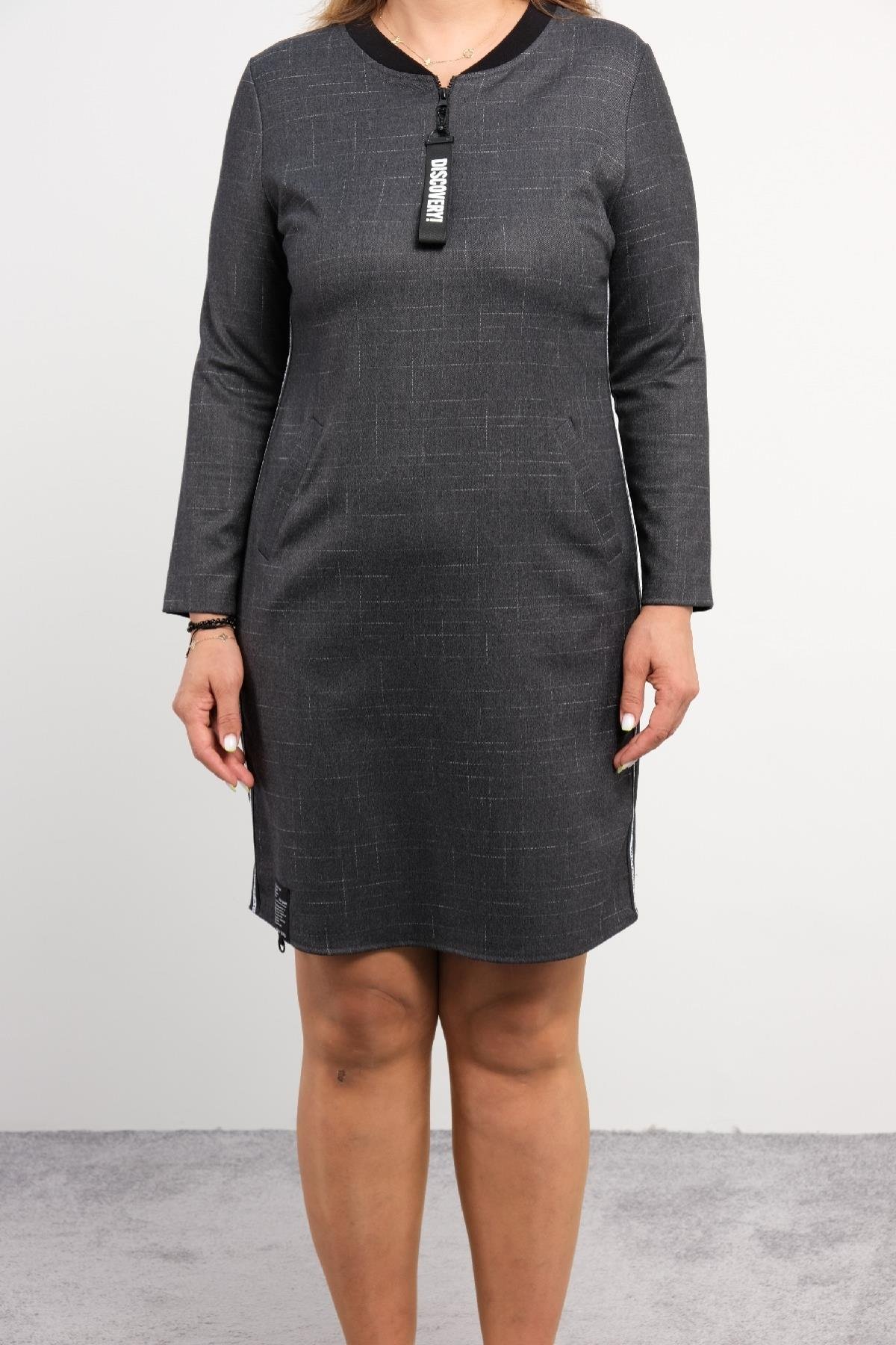  Bu elbise, koyu gri renkte, uzun kollu ve diz üstü uzunluğundadır. Ürünün ön kısmında bir fermuar detayı bulunur ve yanlarda beyaz şerit detayı vardır. Elbisenin bel hizasında iki adet cep bulunmaktadır. Arka kısmı düz ve sade bir tasarıma sahiptir.