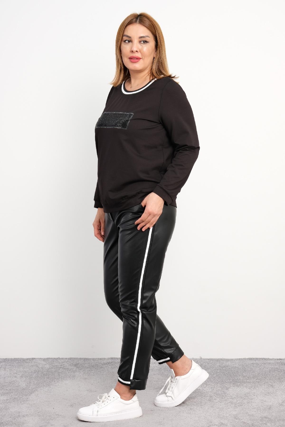 Bu büyük beden kadın ikili takım, rahat ve şık bir seçenektir. Sweatshirt siyah renkte olup, ön kısmında parlak siyah bir detay bulunmaktadır. Yuvarlak yaka tasarımı, beyaz ve siyah çizgili bir şerit ile çevrelenmiştir. Sweatshirt, manşetleri ve etek ucu 