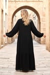 فستان أسود طويل بأكمام بالونية مع تطريز البرسيم على الجهة الأمامية وتنورة مزينة بشراشيب