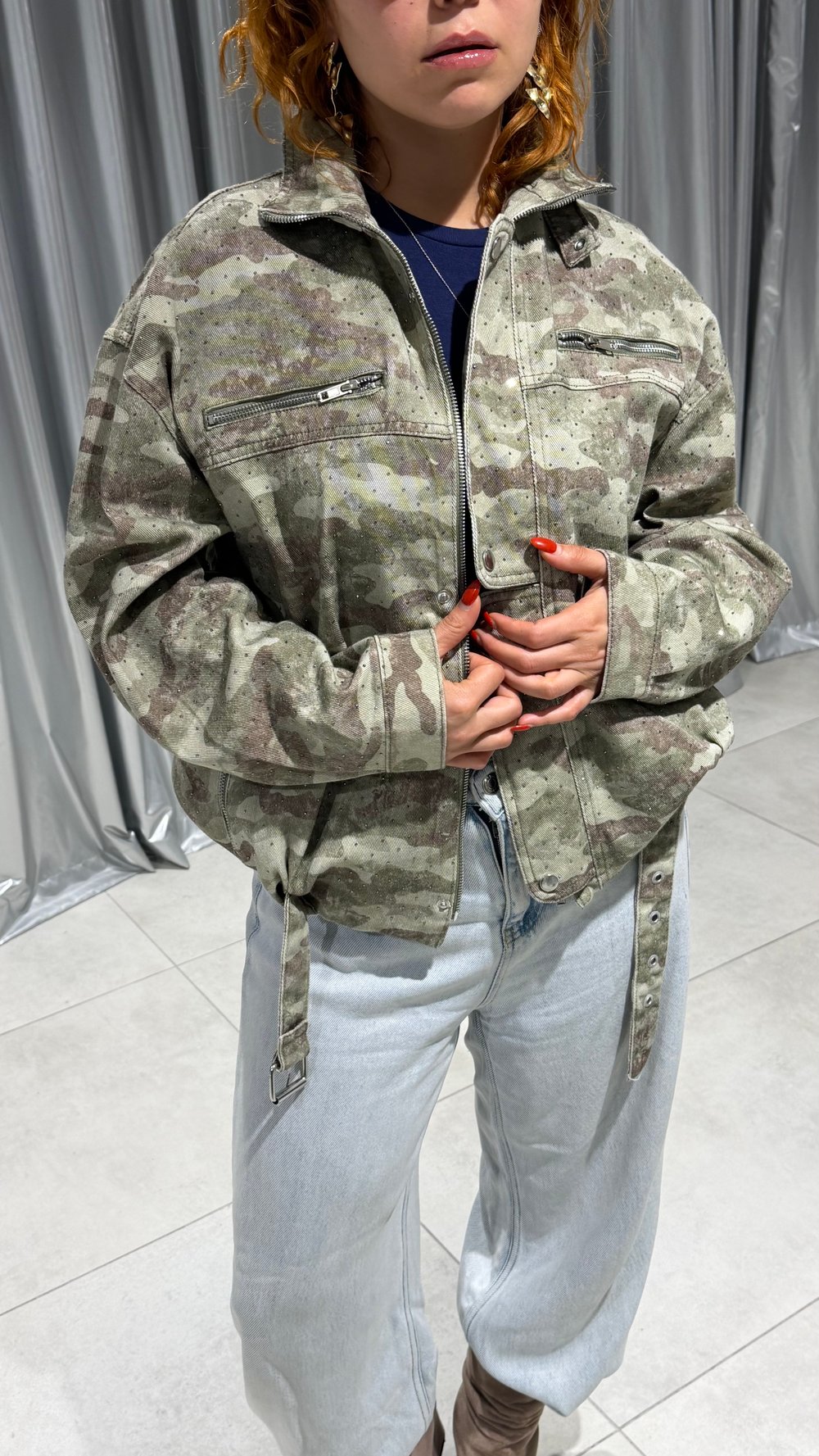 Kamuflaj desen, dik yaka ve metal detayları bir araya getiren ceket modeli.